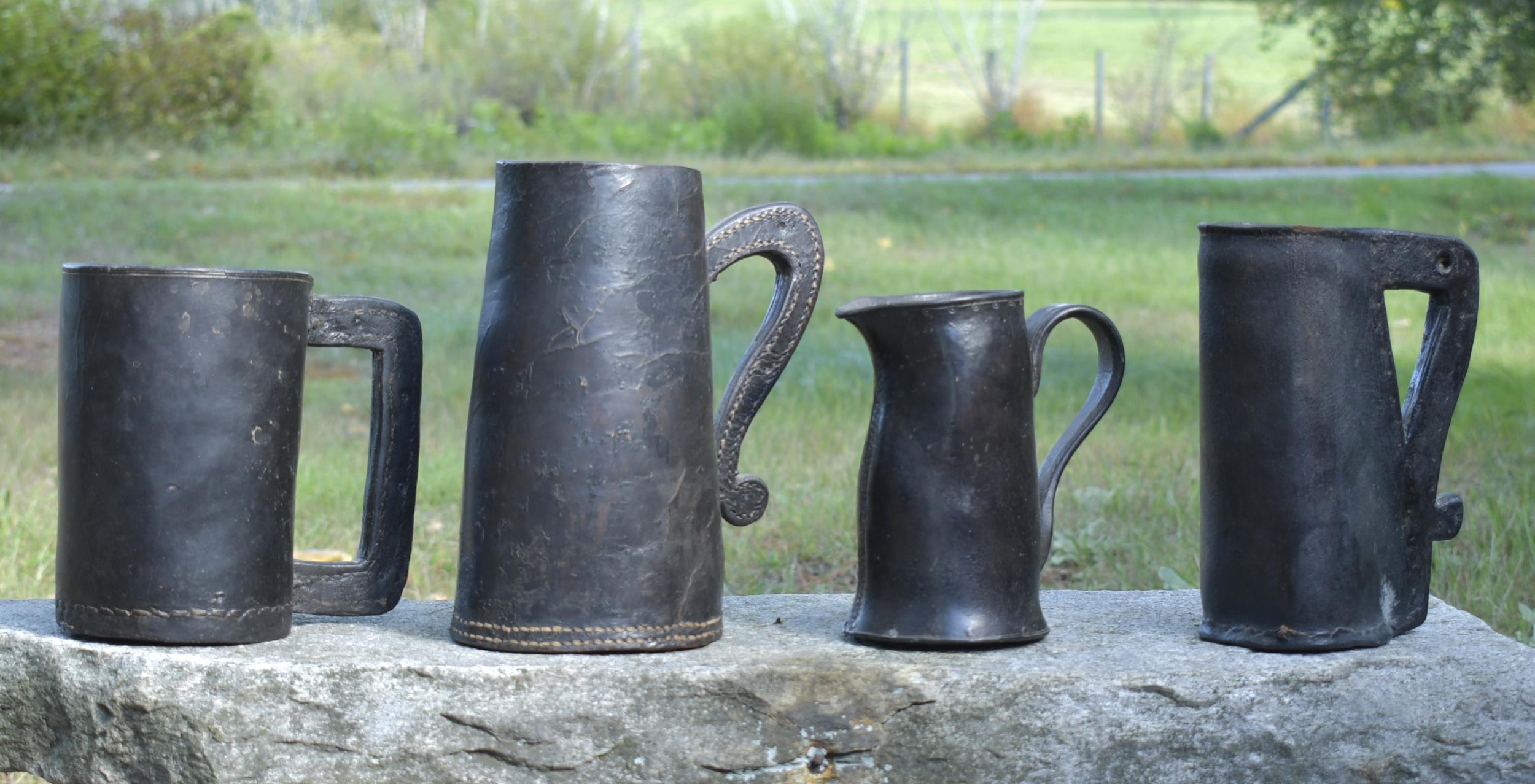 FOUR EARLY LEATHER TANKARDS. 18th
