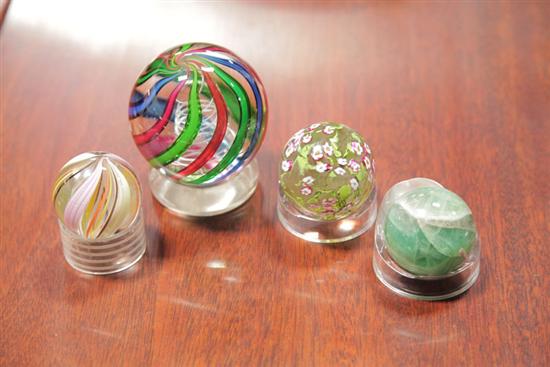 FOUR GLASS MARBLES. Large marble