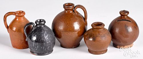 FOUR SMALL REDWARE JUGS AND A BANK,