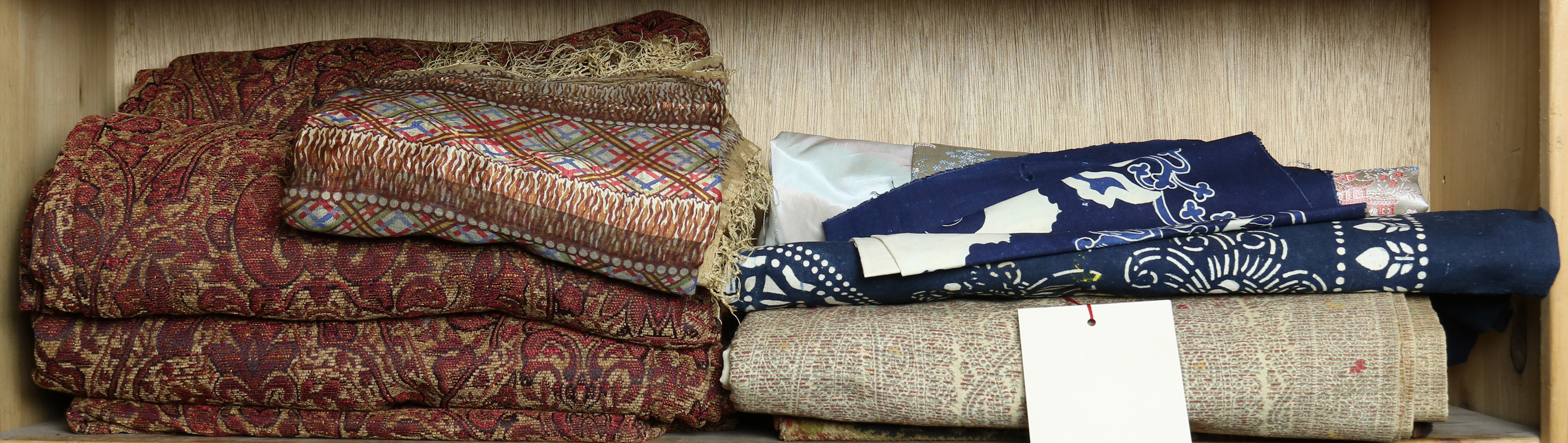 ONE SHELF OF TEXTILES AND SHAWLS