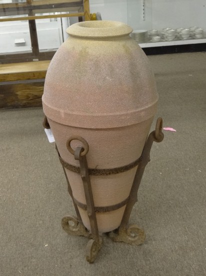 Poured stone jar in metal stand.