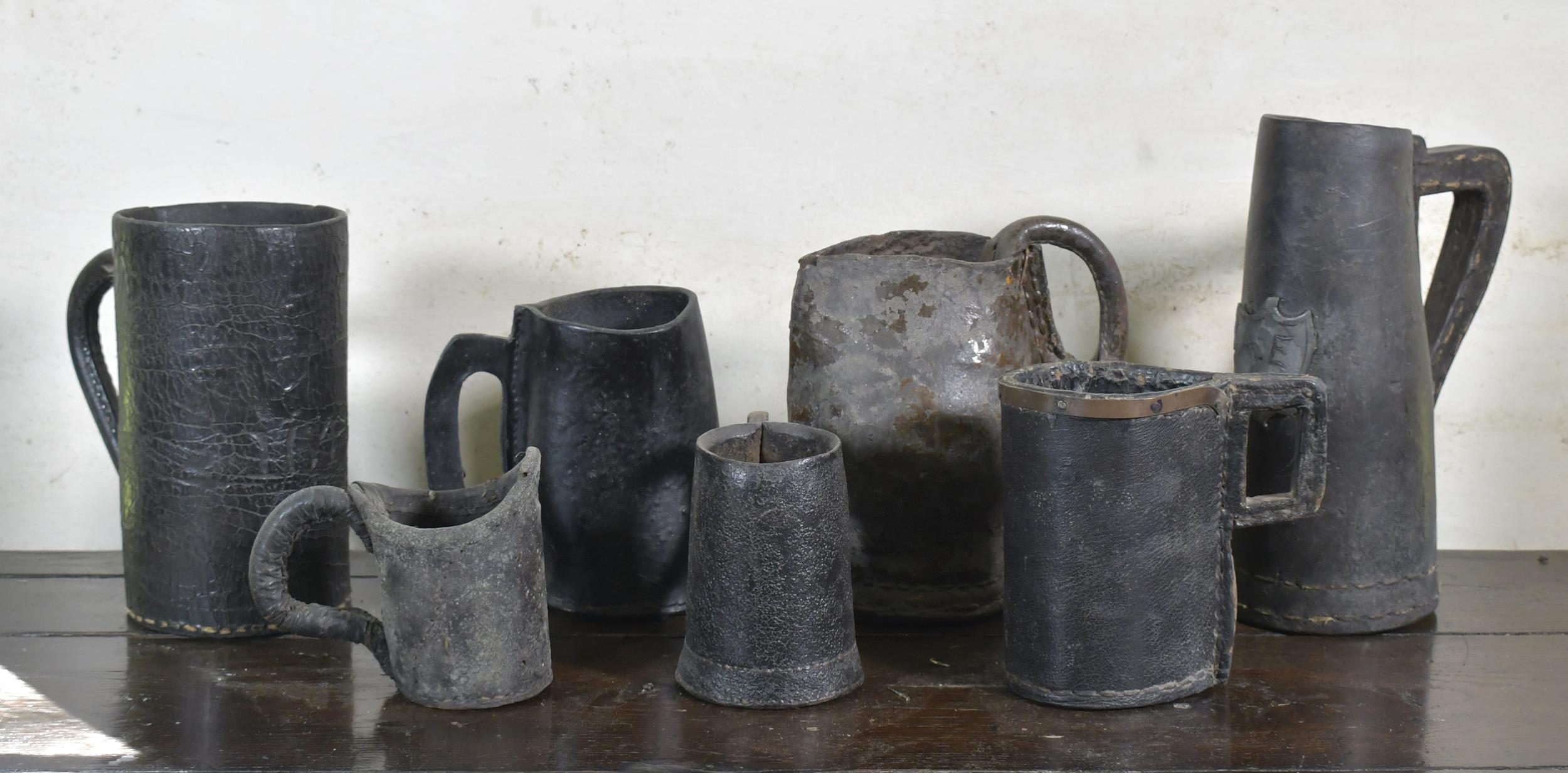 SEVEN EARLY LEATHER TANKARDS AND
