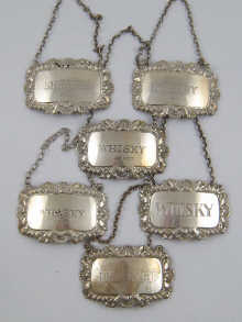 Six silver wine labels ranging in