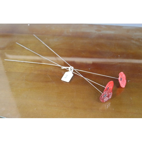 Three glass poppies on metal stems,