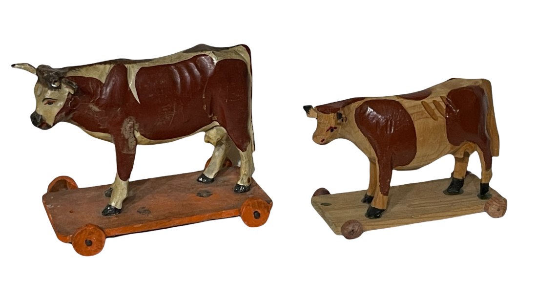 TWO WOODEN COWS ON WHEELED BASES
